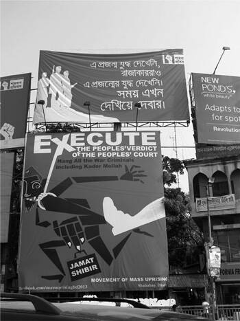 Large sign among others on a street is titled Execute, the peoples' verdict of the peoples' court, hang all the war criminals including Kador Mollah. A white boot kicks a running geometric man colored black with Jamat Shibir in his hand. At the bottom is the phrase Movement of mass uprising.